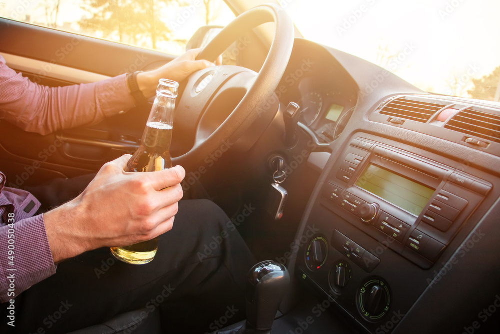 Man drinking alcohol while driving in his car on sunset - obrazy, fototapety, plakaty 