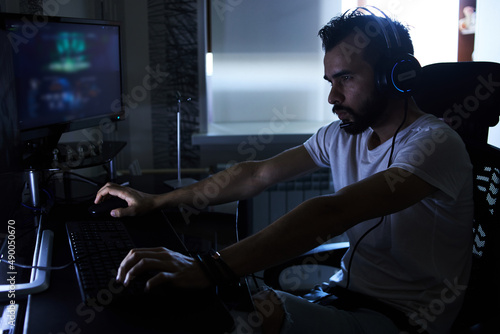 a young 30-year-old gamer is sitting at a computer, playing computer games, nervous, angry, worried.selective focus with low depth of focus