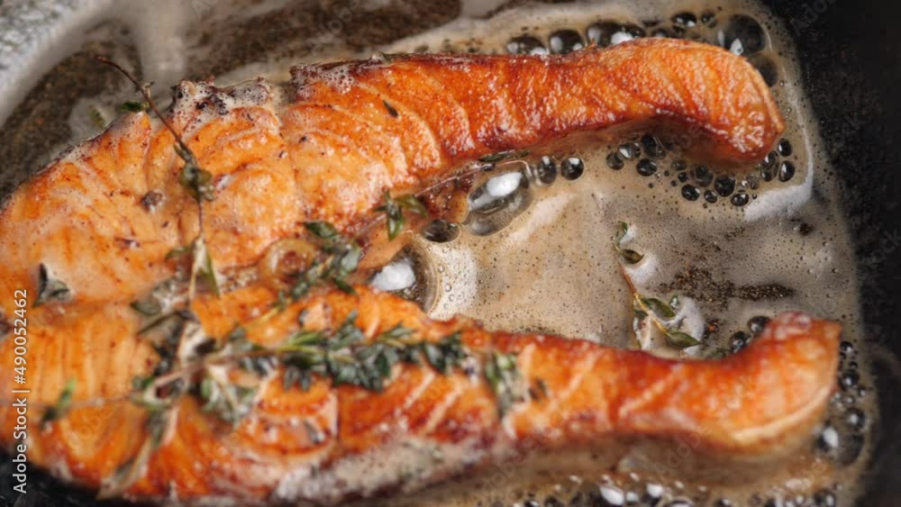 salmon is fried in a pan by the chef. restaurant food. butter bubbles nicely around the fish steak. salmon is fried in a pan by the chef. restaurant food. butter bubbles nicely around the fish steak.