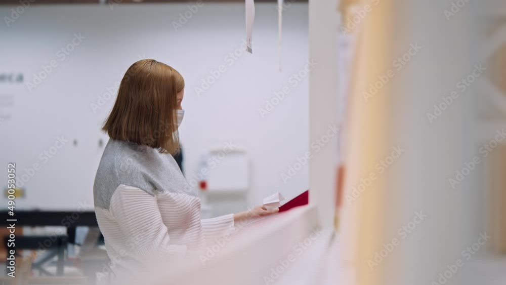 A woman with a mask in a store near the shelf looks at the box slowmotion A woman with a mask in a store near the shelf looks at the box slowmotion