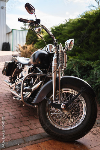 Motocykl typu chopper stojący na podjeździe pod garażem.