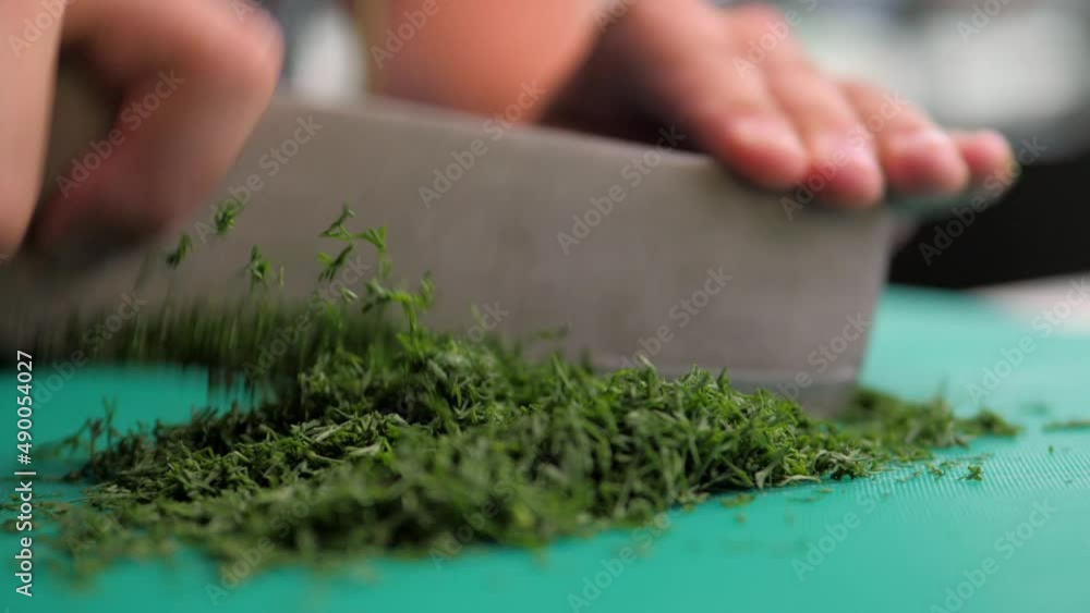 the dill is finely chopped with a knife.France.fresh dill with care, cut into small pieces on a cutting board. dark background. close-up. france restaurant cuisine. Slow motion. the dill is finely chopped with a knife.France.fresh dill with care, cut into small pieces on a cutting board. dark background. close-up. france restaurant cuisine. Slow motion.