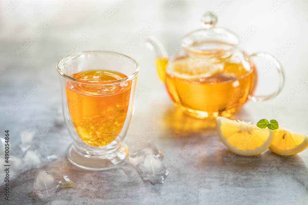 iced lemon fruit tea in a glass cup and tea pot isolated over plain grey background, no people. food summer refreshment concept iced lemon fruit tea in a glass cup and tea pot isolated over plain grey background, no people. food summer refreshment concept