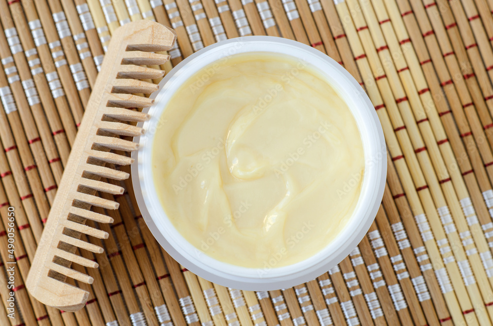 Yellow hair mask (banana face cream, shea butter mask, mango body butter) in a small white container. Natural skin and hair treatment concept. Top view, copy space. Yellow hair mask (banana face cream, shea butter mask, mango body butter) in a small white container. Natural skin and hair treatment concept. Top view, copy space.