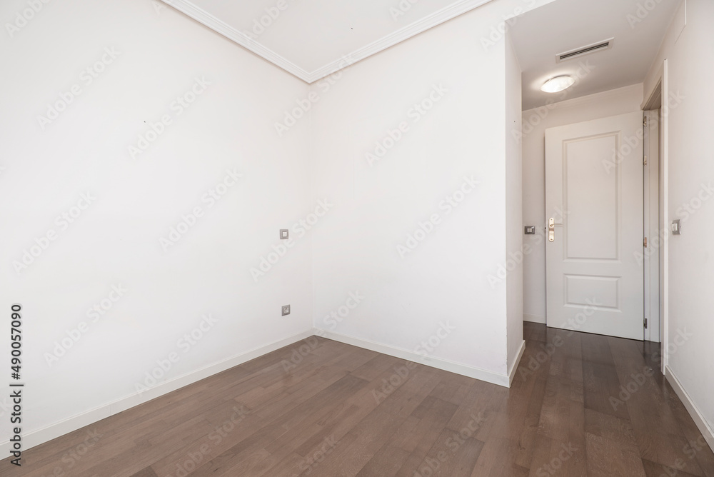 Empty room with dark wooden floors, white painted walls and white lacquered woodwork
