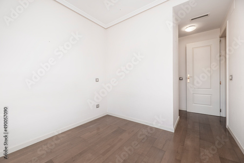 Empty room with dark wooden floors  white painted walls and white lacquered woodwork