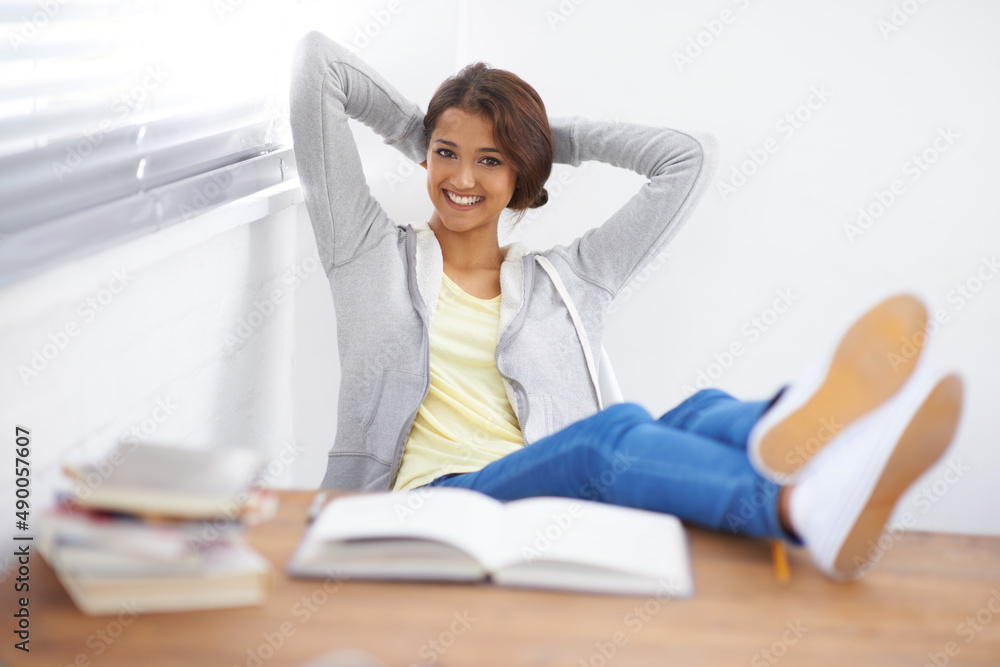 Happy to be having a break. Shot of a cute young college student with her feet up and hands behind her head. Happy to be having a break. Shot of a cute young college student with her feet up and hands behind her head.