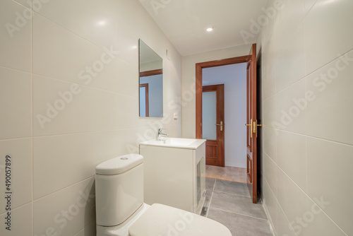 Bathroom with square white porcelain sink with square frameless mirror and mahogany wood door