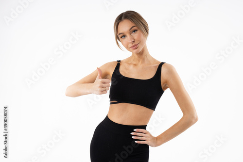 slim young woman in black sportswear with hand gesture 