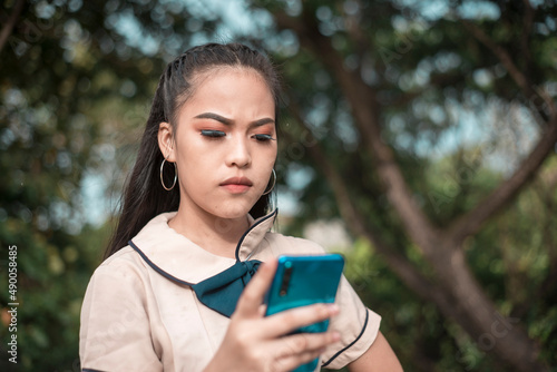 A young asian student is displeased after receiving a message or reply filled with obscenities or profanities on her phone. Dealing with a troll or basher on her social media. photo