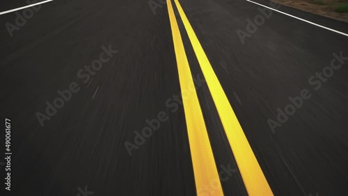 Front pov view of fast car driving on asphalt road with double yellow lines converge
