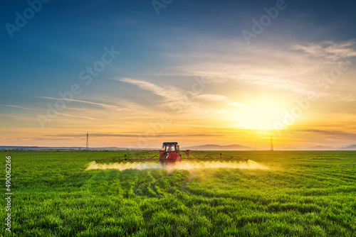Tractor spray fertilizer spraying pesticides on green field, agriculture background concept.