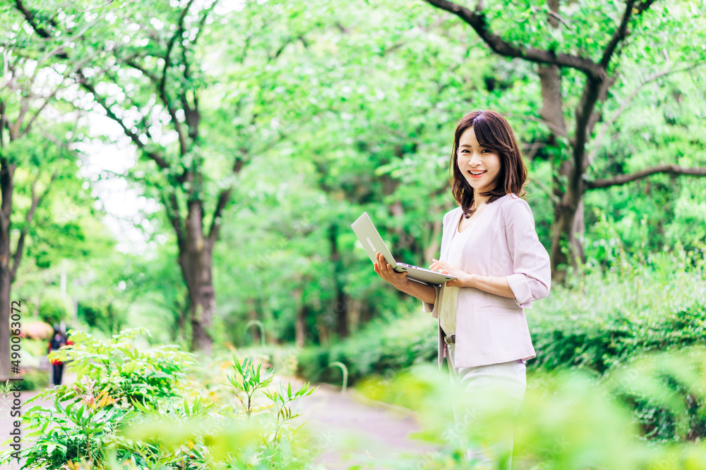外でパソコンを使う若いビジネスウーマン