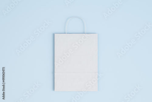 Close up of empty white paper bag on blue background. Shopping concept. Mock up, 3D Rendering.