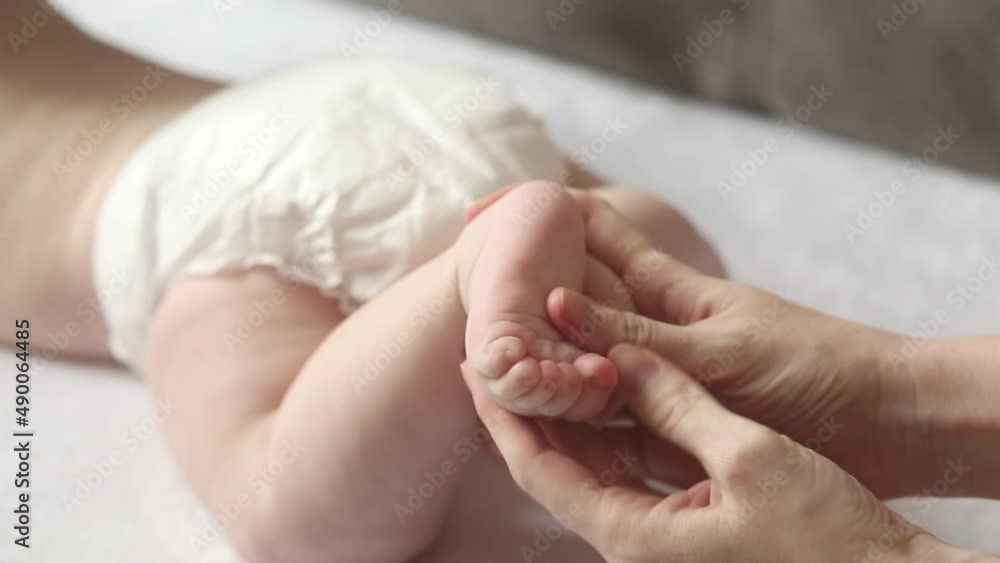 Mom massages the legs of a newborn. Happy parenting. The concept of education and care. Paternity. father's day Mom massages the legs of a newborn. Happy parenting. The concept of education and care. Paternity. father's day