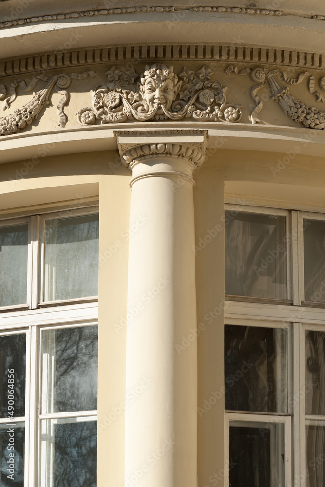 Obraz premium A part of the facade of an old building with beautiful stucco decoration and bas-relief head of the mythical man