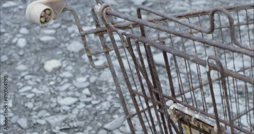 Rusty shopping trolley on the edge of a river after a flood.