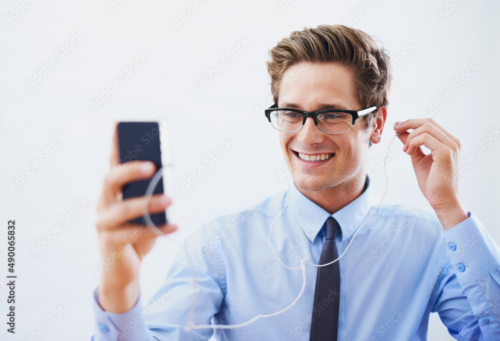 Choosing his best tracks. A handsome young businessman choosing a song from his smartphones playlist. Choosing his best tracks. A handsome young businessman choosing a song from his smartphones playlist.