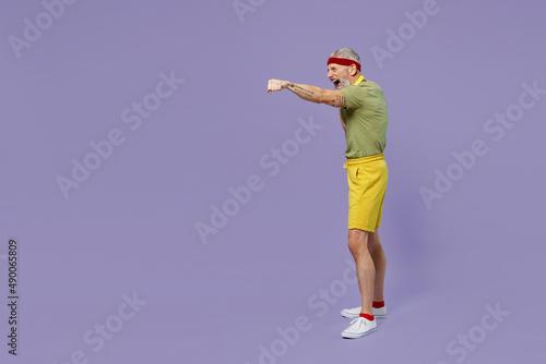 Full size body length elderly gray-haired bearded man 40s years old in headband khaki t-shirt look aside stand in boxing pose punch isolated on plain pastel light purple background studio portrait
