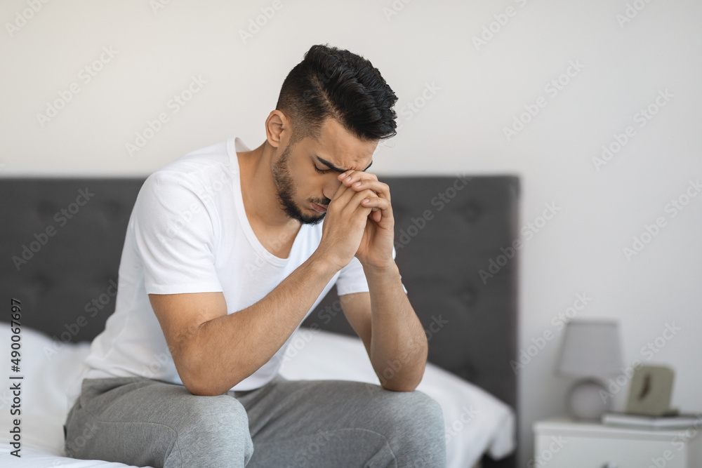 Portrait Of Sad Pensive Middle Eastern Man Sitting On Bed At Home Portrait Of Sad Pensive Middle Eastern Man Sitting On Bed At Home