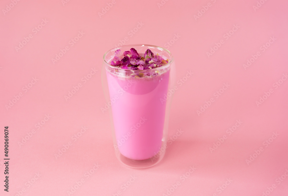 Pink rose milk with rose petals in a double walled glass. Healthy drink moon milk. Pink rose milk with rose petals in a double walled glass. Healthy drink moon milk.