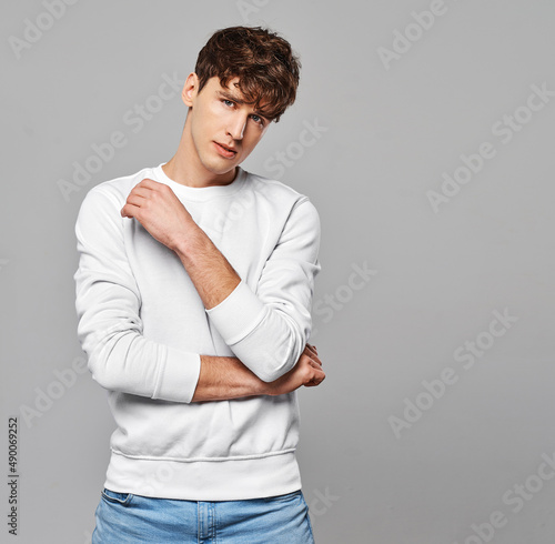 Young handome man in white sweatshirt over gray background photo