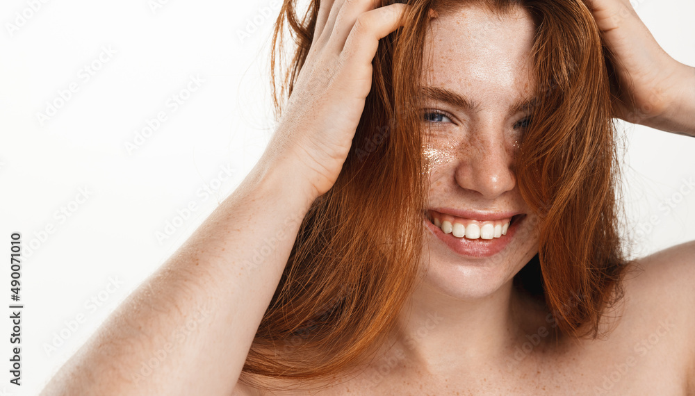 Fototapeta premium Beauty, head and shoulders concept. Beautiful happy plus size woman, redhead girl touches her hair and smiling, laughing carefree with glitter on glowing beauty face, white background