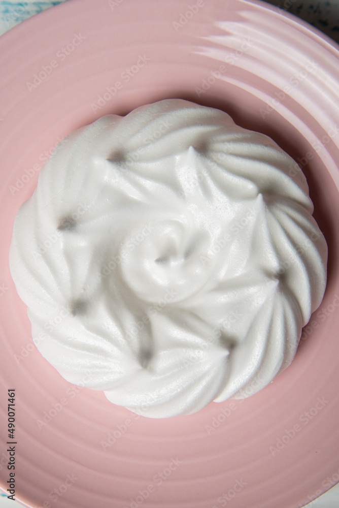 One large meringue on a pink saucer. Home confectionery flatley. Old retro white and blue table. One large meringue on a pink saucer. Home confectionery flatley. Old retro white and blue table.