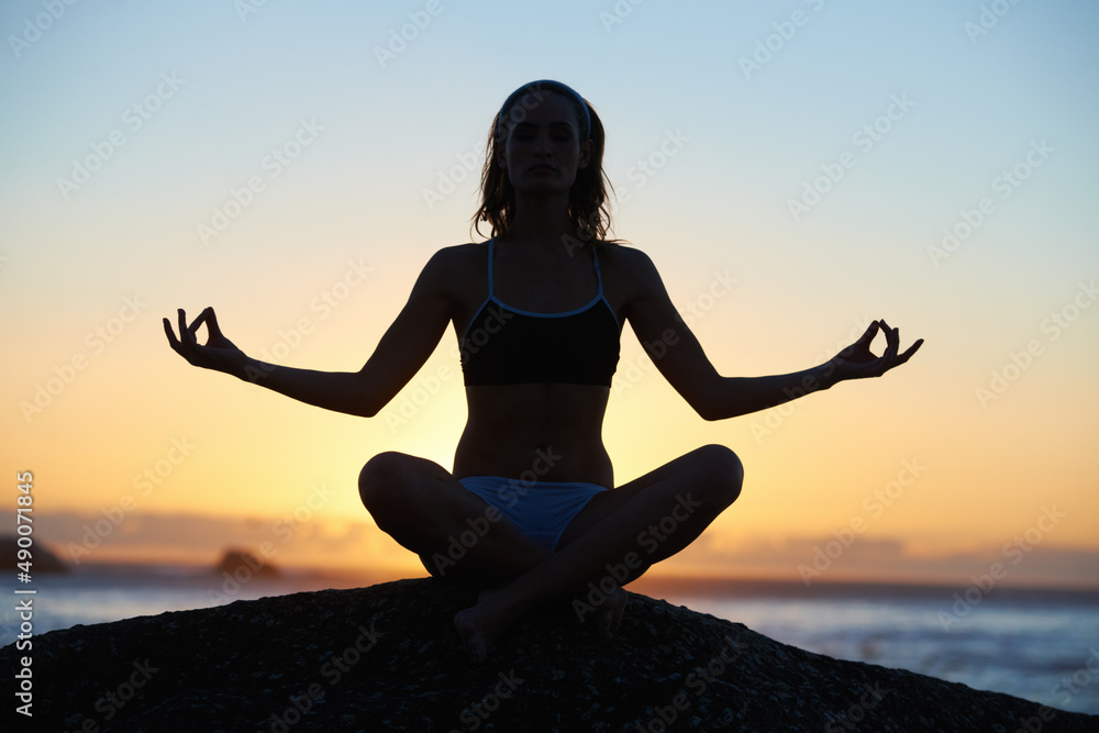 In touch with nature. Silhouette of a young woman doing a yoga pose against an orange sunset. In touch with nature. Silhouette of a young woman doing a yoga pose against an orange sunset.