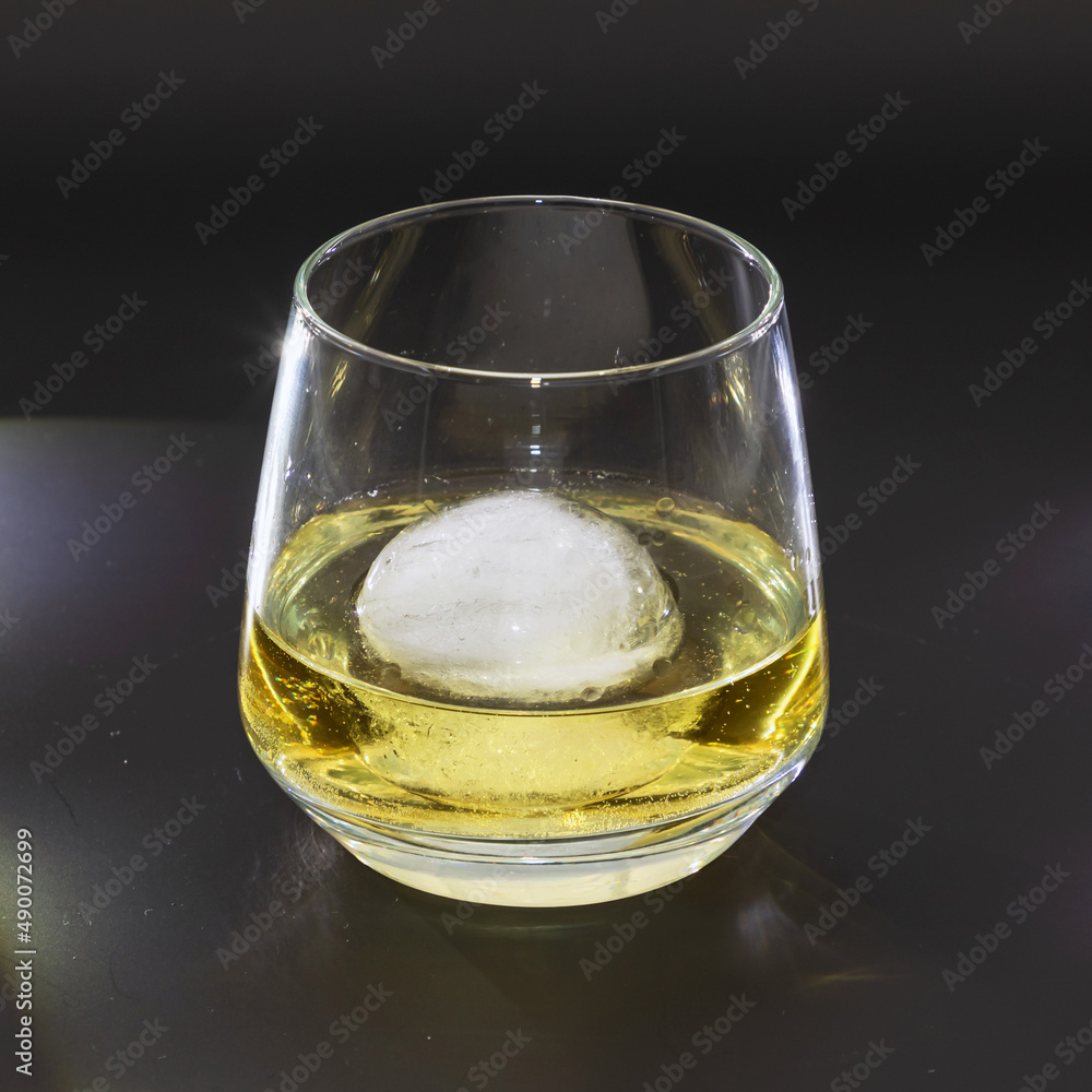 Studio photograph of a glass whisky on the rocks with an ice cube on black background Studio photograph of a glass whisky on the rocks with an ice cube on black background