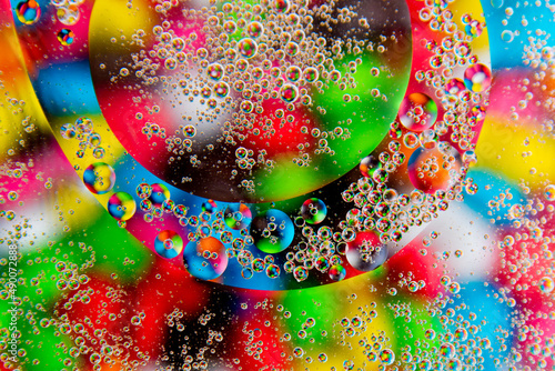 Bubbles in oil in water on a colorful candies abstract background.