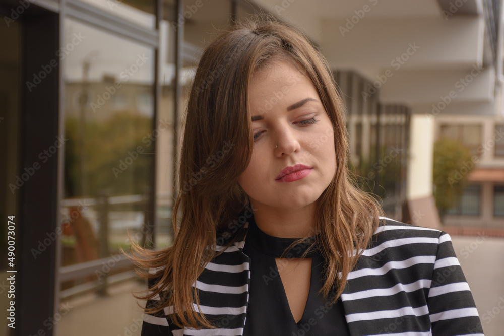 Ukrainian woman in a striped sweater is sad on the street Ukrainian woman in a striped sweater is sad on the street