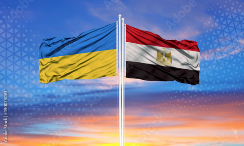 Ukraine and Egypt two flags on flagpoles and blue sky..