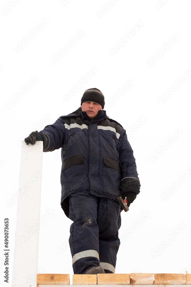 A worker with a board in his hand assembling the frame of a wooden slide