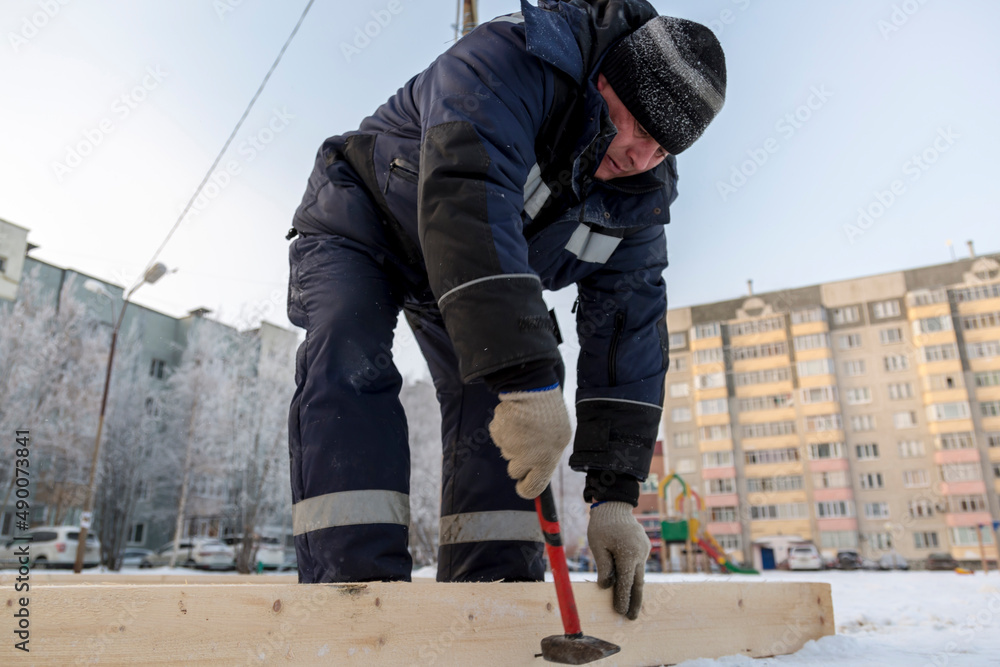Worker in winter overalls with a hammer in his hand