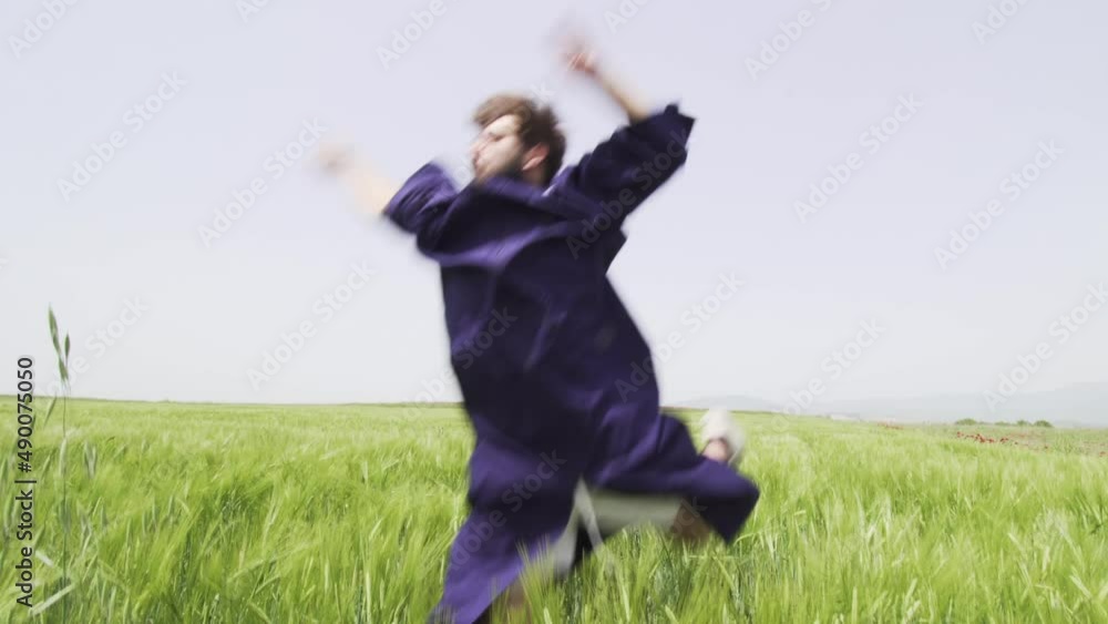 Young man with graduation clothes in a green field throwing hat in the air.. Young man with graduation clothes in a green field throwing hat in the air..