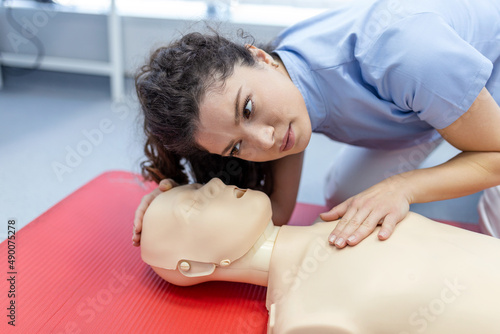 woman practicing cpr technique on dummy during first aid training. First Aid Training - Cardiopulmonary resuscitation. First aid course on cpr dummy. photo