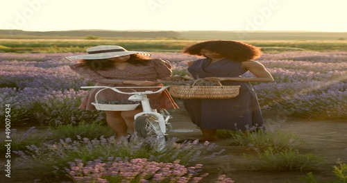 Young multiracial women talkling in lavender field on sunset photo