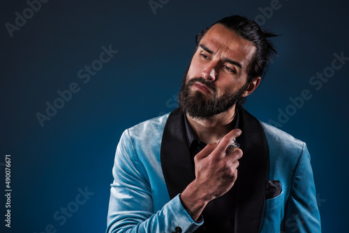 Masculine bearded young man holding a generic bottle of perfume. Male fragrance and perfumery, cosmetics. Masculine perfume. Bearded man holding a bottle of perfume. 