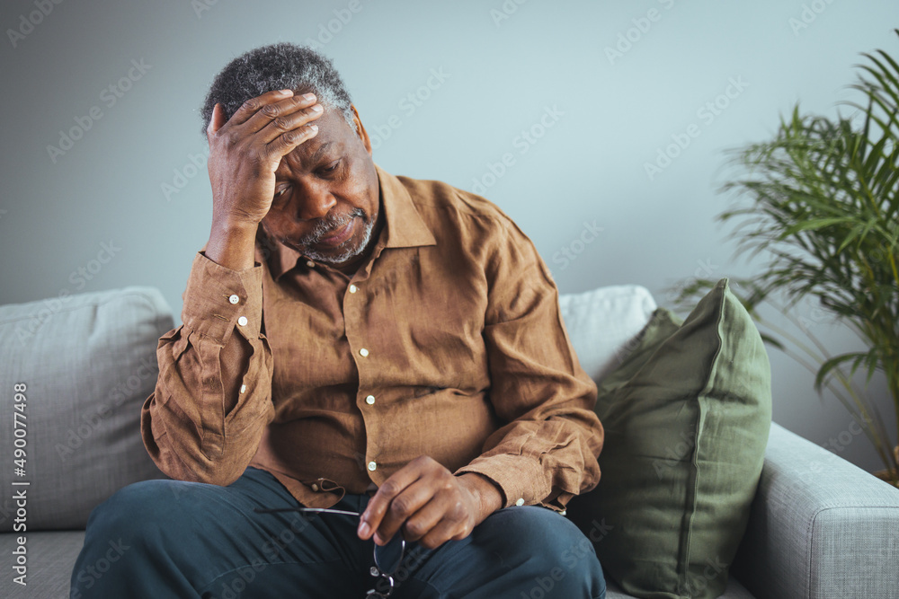 An adult has a headache. He sits and holds his hands on his head in a ...