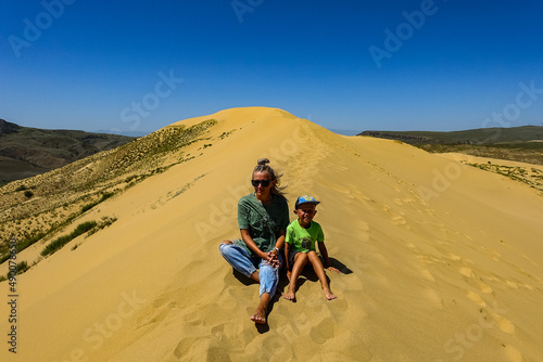 A girl with a child on the sand dunes of Sarykum. The desert in Dagestan. Russia. 2021.