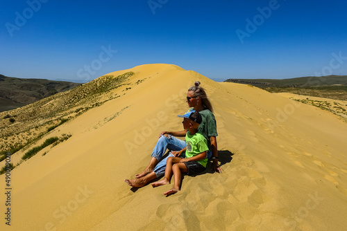 A girl with a child on the sand dunes of Sarykum. The desert in Dagestan. Russia. 2021.
