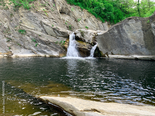 Small mountain waterfall surrounded of rocks and beautiful nature. Kapinovo waterfall in Bulgaria. photo