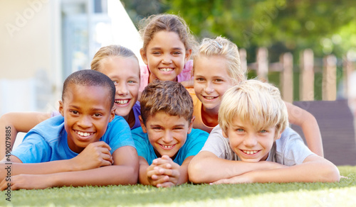 Healthy lifestyles make happy kids. A group of cute primary school kids lying down in pyramid formation outside.