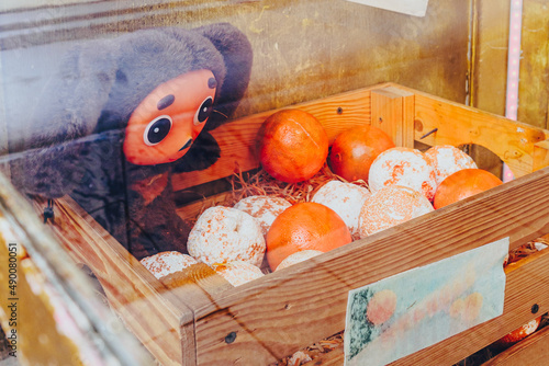 Toy eared Cheburashka and oranges in a wooden box behind glass. Cheburashka is a famous character in a children's cartoon.