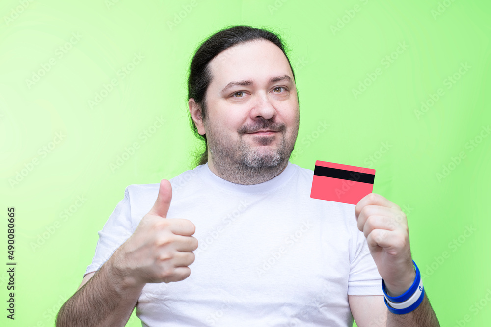 A simple, unshaven middle-aged man holds a plastic card in his hands and rejoices. Bracelet on the wrist in the colors of the Israel flag. A simple, unshaven middle-aged man holds a plastic card in his hands and rejoices. Bracelet on the wrist in the colors of the Israel flag.