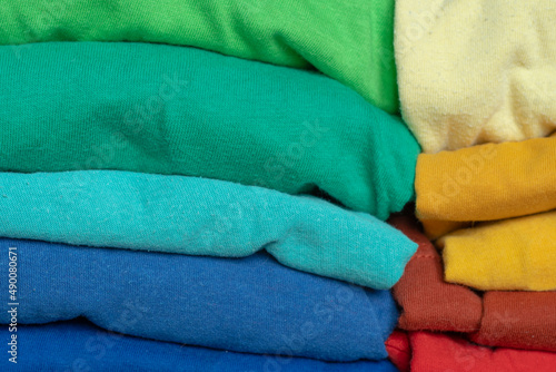 Stacks of multicolored fabrics in cool and warm colors are compared next to each other. Background with folded clothes with blank space for information. T-shirts of different colors © Николай Батаев