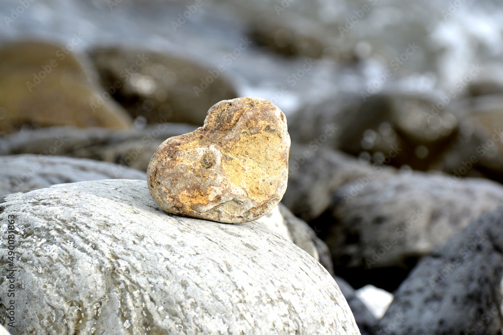 Heart shape stone against background of beach. Summer sunny day. Love, wedding and Valentine day concept. Finding beautiful and interesting stones. Beach vacation. 