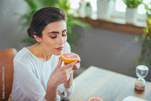 Sick woman trying to sense smell of half fresh orange  has symptoms of Covid-19  corona virus infection - loss of smell and taste. One of the main signs of the disease.