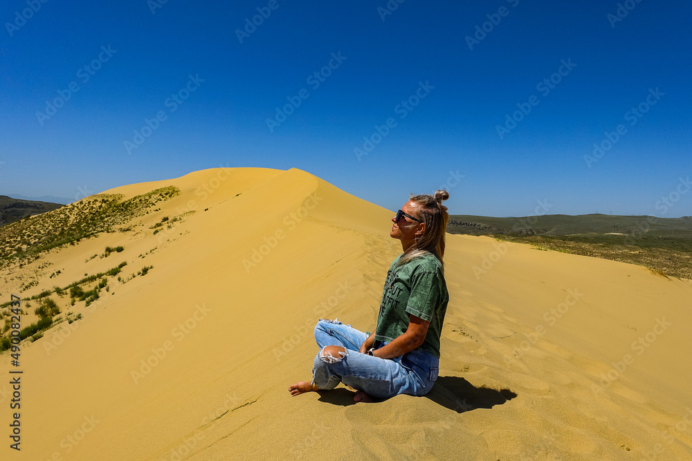 A girl on the sand dunes of Sarykum. The desert in Dagestan. Russia. 2021.